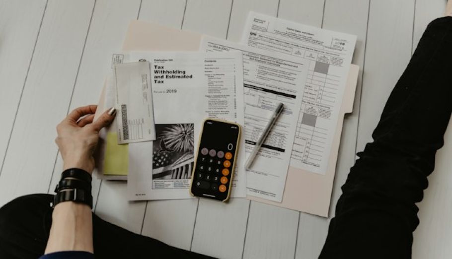 Personne consultant des documents financiers avec une calculatrice, symbolisant le bilan patrimonial de rentrée